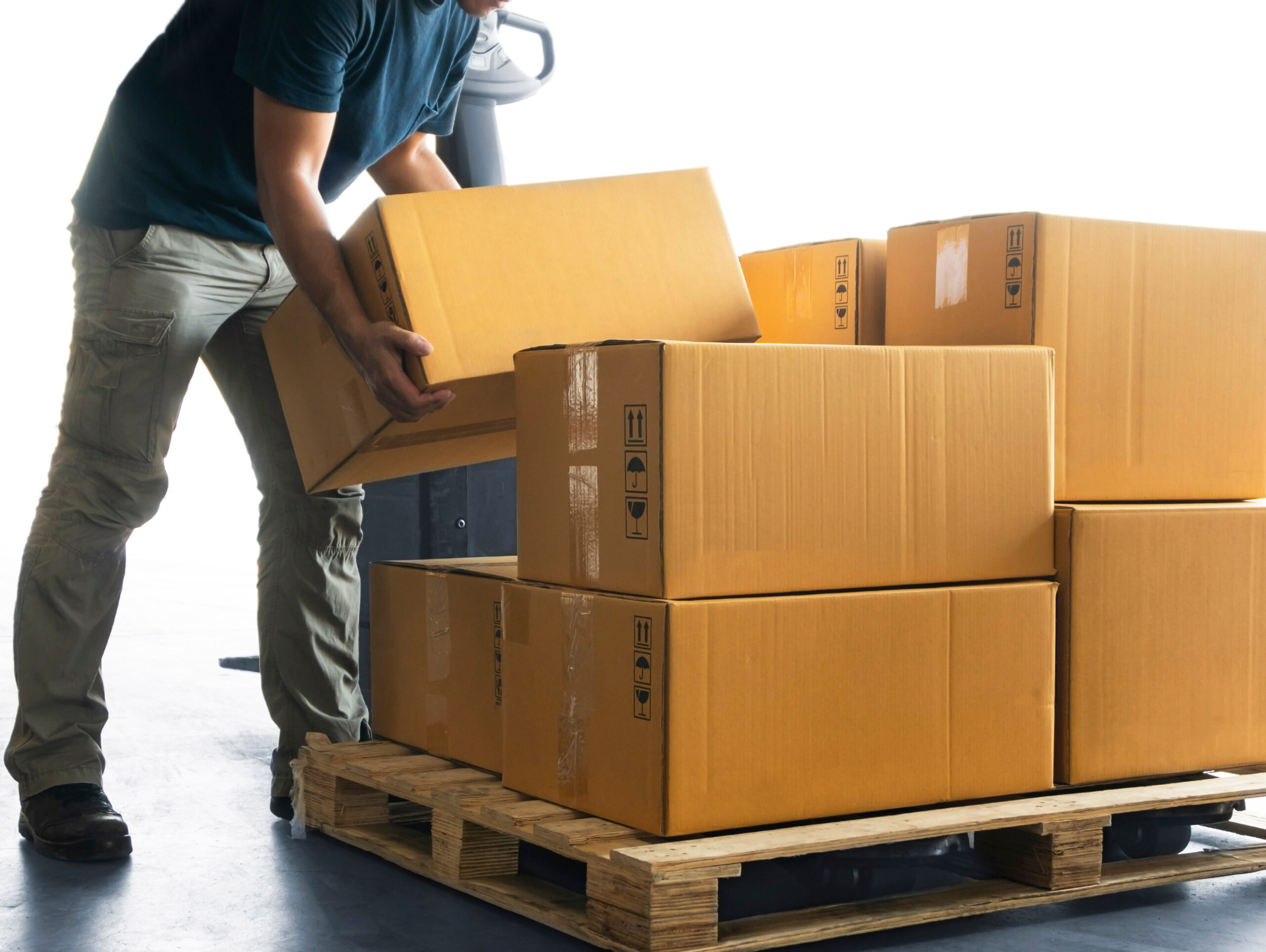 Workers Lifting Packaging Boxes on Pallets Racks in The Warehous